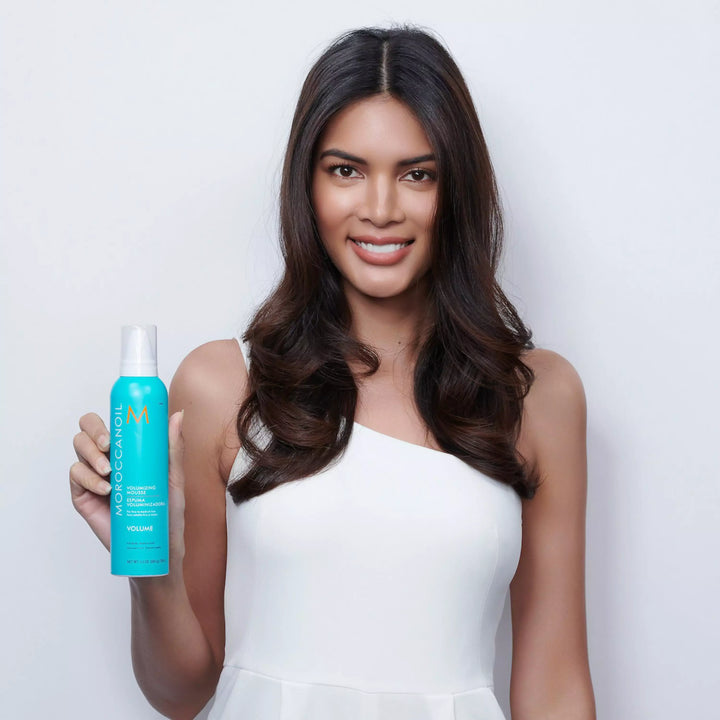 Moroccanoil Volumizing Mousse image of model holding bottle