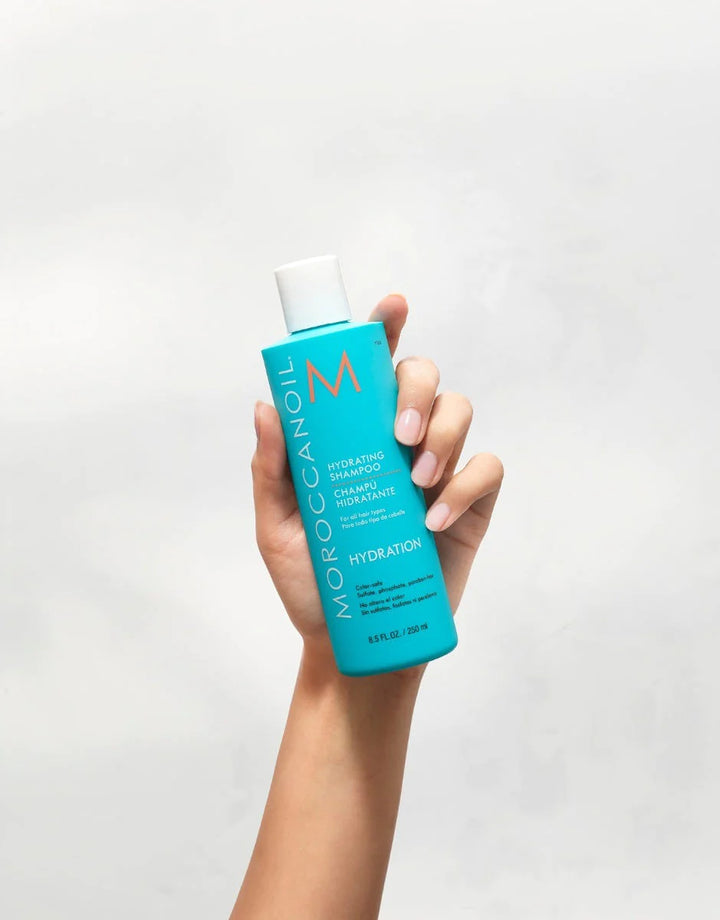 Moroccanoil Hydrating Shampoo Model holding 8.5 oz bottle