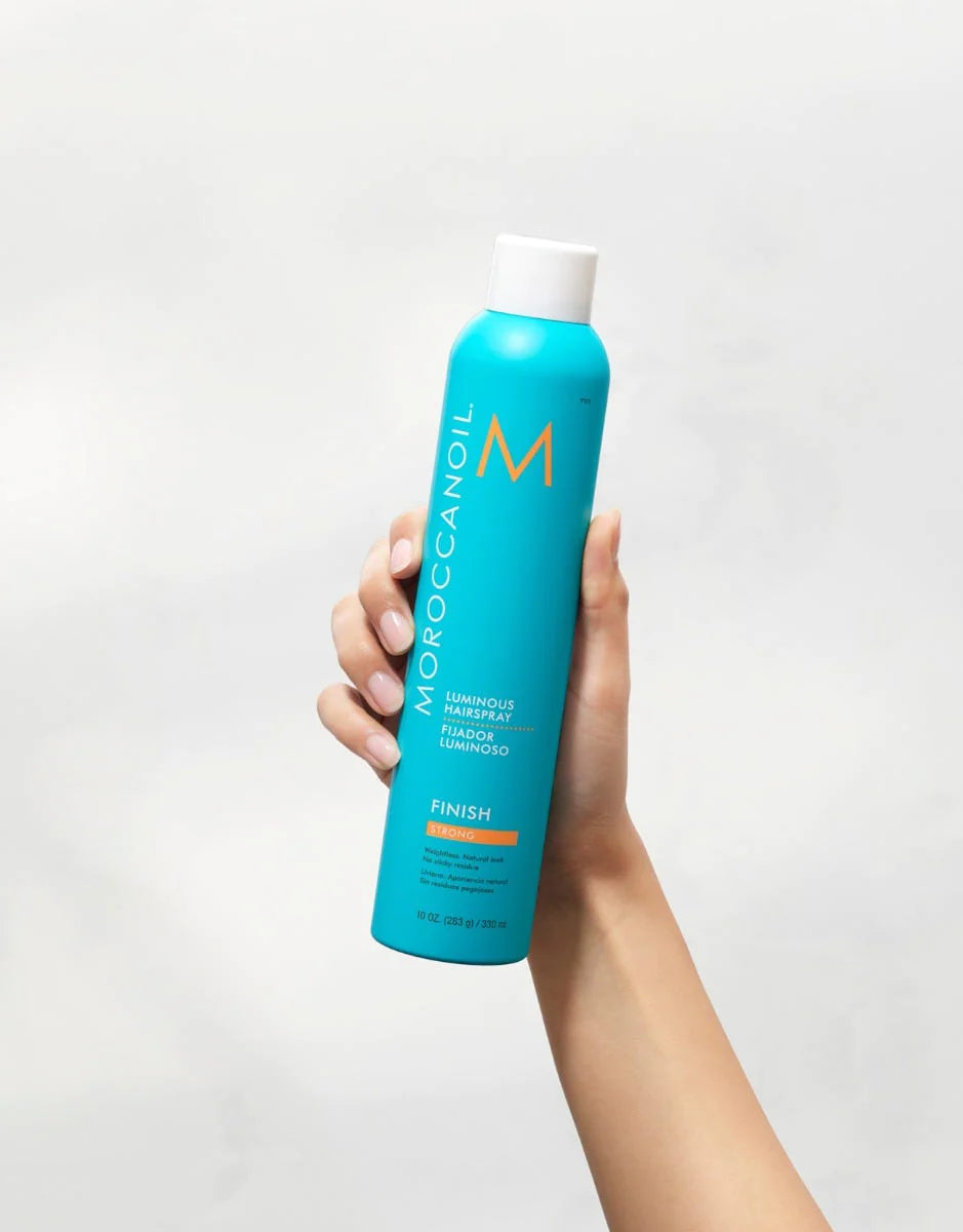 Moroccanoil Luminous Hairspray Strong image of model holding 10 oz bottle