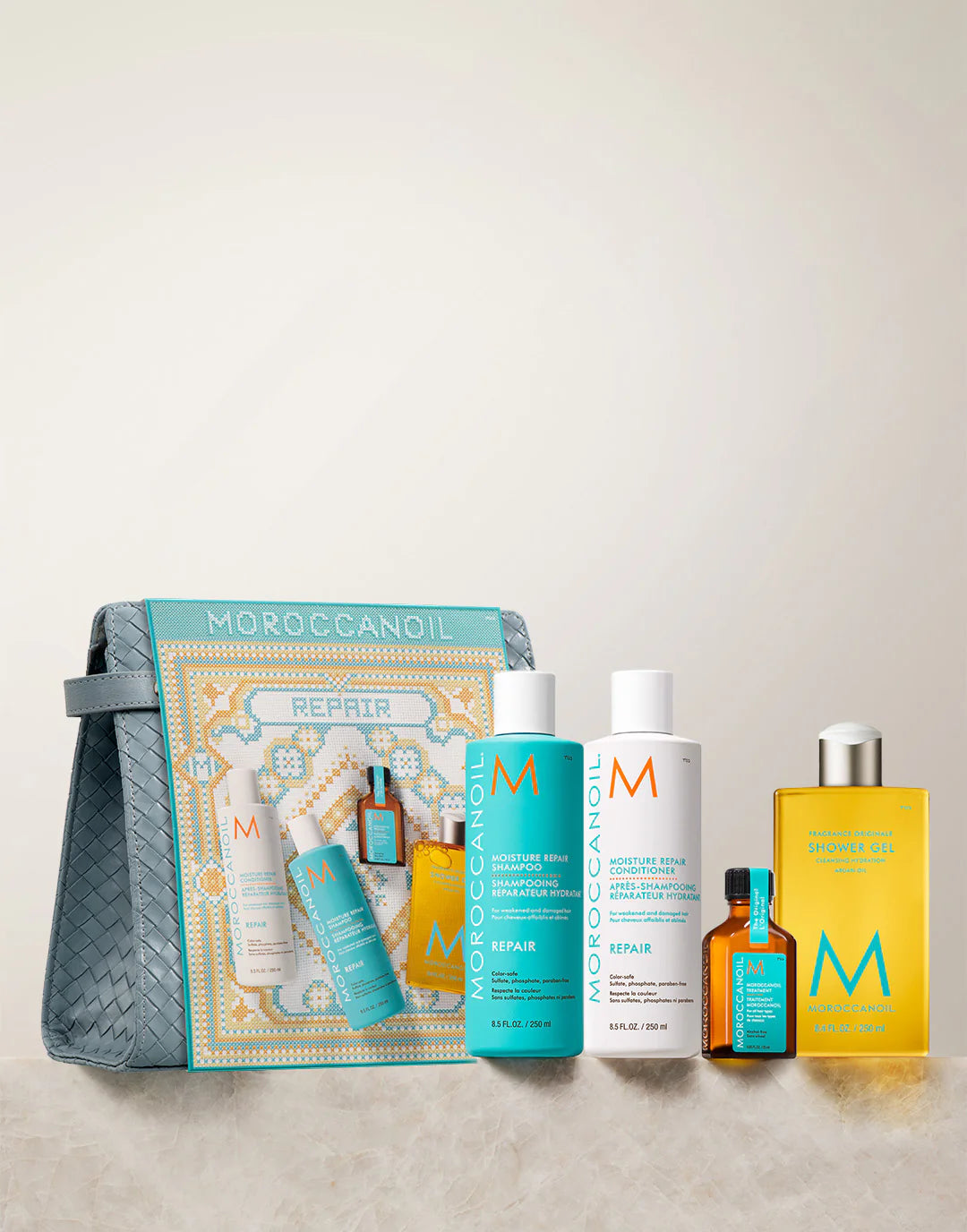 Moroccanoil hair care products including bottles and a pouch on a beige background